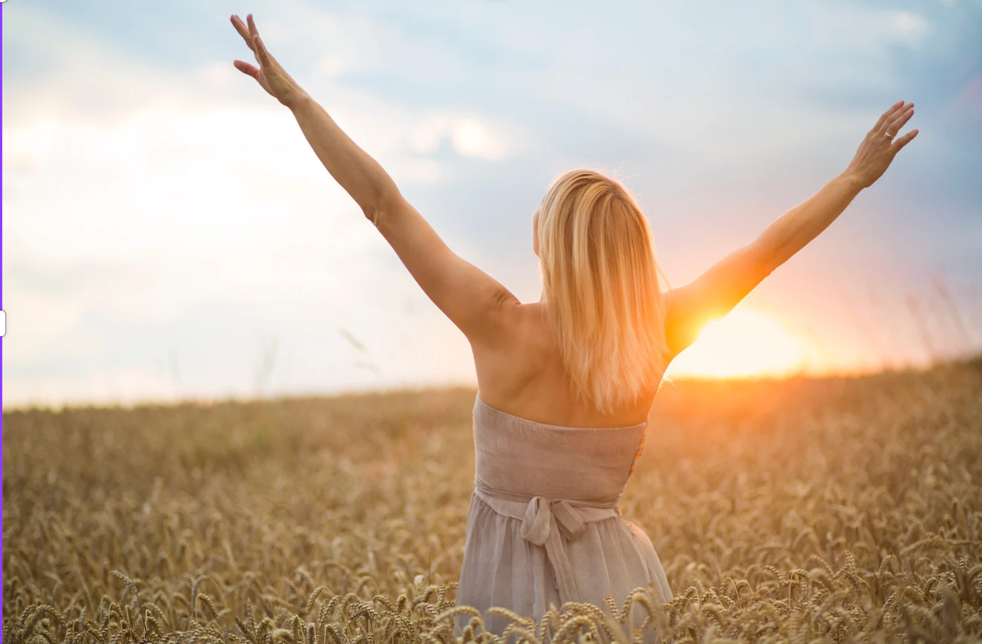 Woman with arms raised in a sunlit field, feeling free and joyful